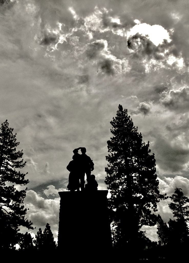 Silhouetted Donner Party Monument beneath dramatic clouds and sunlight