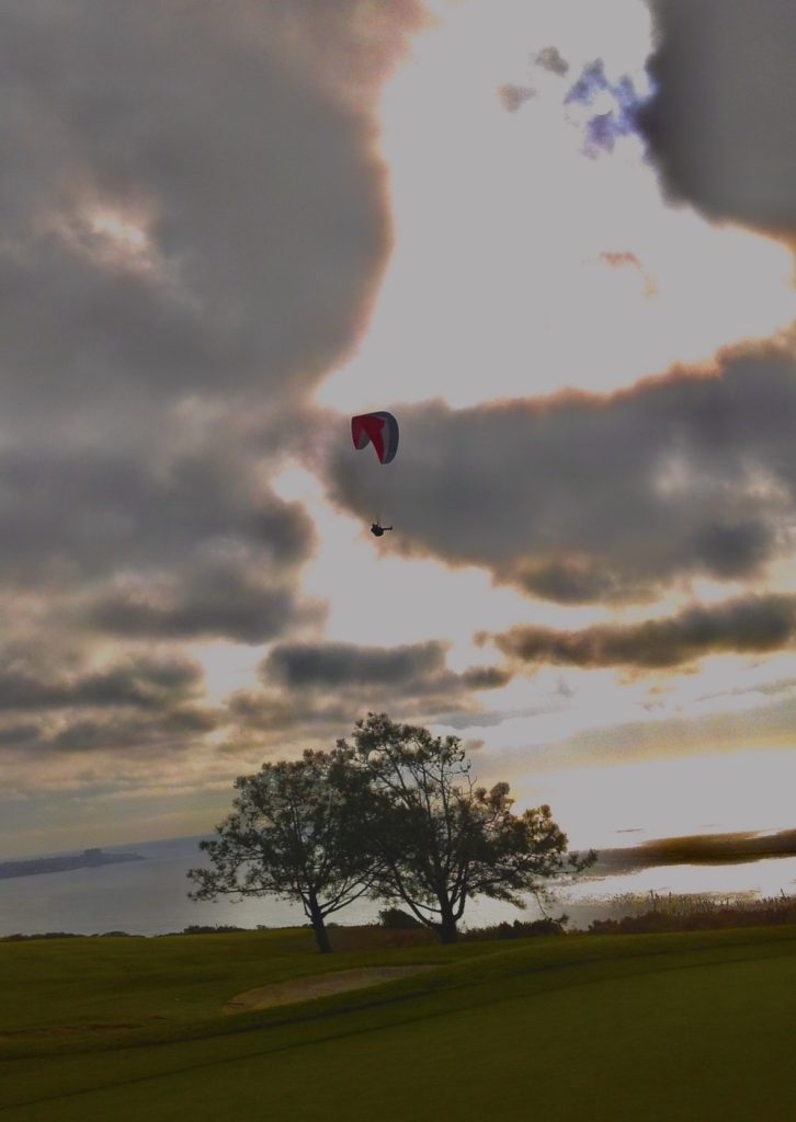 A paraglider above Torrey Pines beneath dramatic clouds